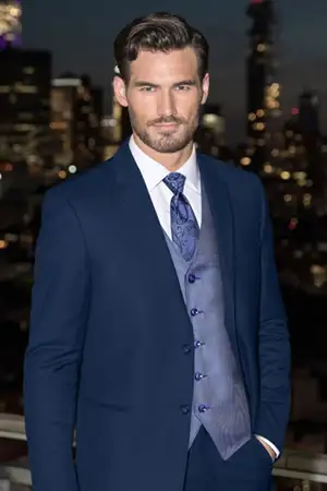 Man selected his style and is wearing a blue suit with city in the background