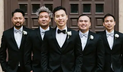 Wedding party in all black tuxedos in a line.